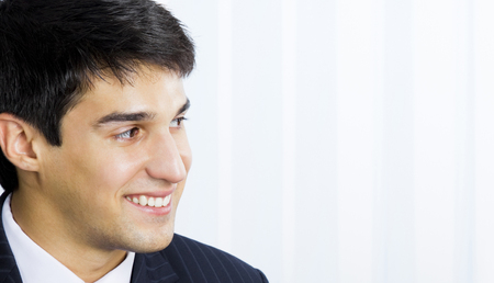 Portrait of happy smiling young businessman at office, with copyspaceの写真素材