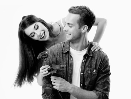 Portrait of young happy hugging couple with flower, close to each other, with smile. Caucasian models in love, relationship, dating, flirting, lovers, romantic concept. Black and white.の写真素材