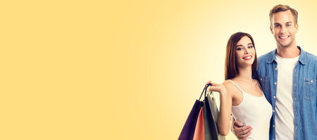Happy couple with shopping bags, standing close to each other and looking at camera with smile. Love, holiday sales, shop, retail, consumer concept. Copy space for some text, or slogan.の写真素材