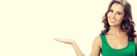 Portrait of smiling beautiful young woman showing something, in smart green casual clothing, with empty copyspace area for slogan, text or advertisiment.の写真素材