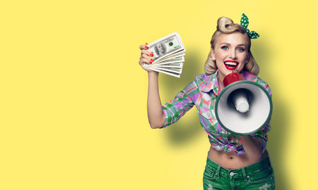 Portrait of beautiful pinup girl. Happy excited smiling woman holding cash money banknotes and...