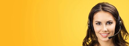 Call center servise. Customer support phone sales female operator in headset with copy space area for some text, imaginary, product or slogan, over yellow orange color background. Front view.の写真素材