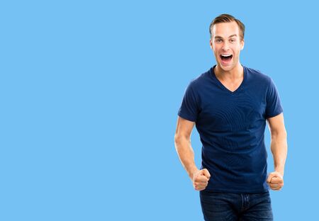 Yes, I did it! Very happy young man, isolated over blue color background. Emotions and success concept. Excited male model with open mouth, in blue smart casual wear at studio picture. Copy space.の写真素材