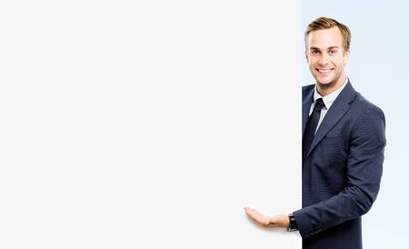 Happy confident successful businessman showing blank board, isolated against grey background. Empty copy space for some slogan or advertising sign text. Success in business concept.の写真素材