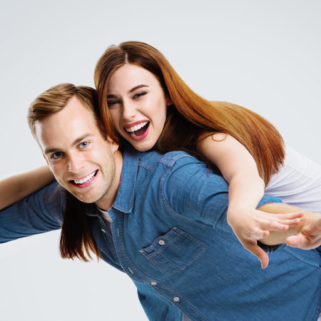 Portrait image of expressive amorous funny laughing couple. Standing piggy back ride models in love...