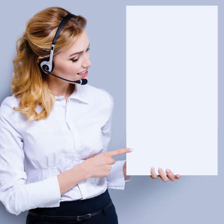 Call Center Service concept - customer support or sales agent. Businesswoman or caller or receptionist phone operator pointing at sign board with copy space. Helping, answering, consulting. Square.の写真素材