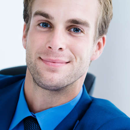 Portrait of young happy smiling businessman in blue suit. Success in business, job and education concept shot. Square composition image.の写真素材