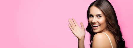 Portrait studio image of happy gesturing smiling young beautiful brunette woman, isolated over rose pink color background. Copy space area for some text or slogan.の写真素材