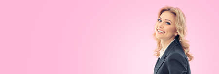 Portrait of happy smiling young businesswoman in grey confident suit, isolated over pink color background. Business studio concept. Copy space blank area for text.の写真素材
