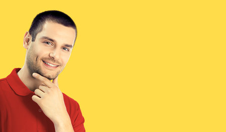 Portrait of happy smiling dreaming man in red casual clothing, isolated over yellow colour...