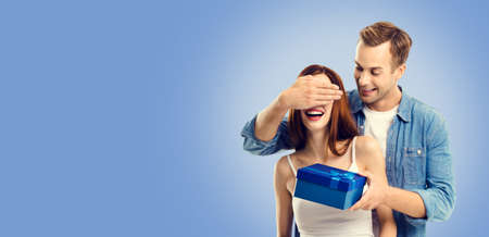 Love, holiday sales, shop, rebates, discounts offers concept - happy amorous couple with blue gift box. Blue color background. Copy space for text. Valentines Day.の写真素材