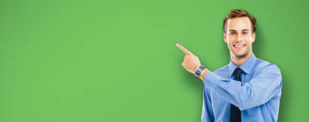 Happy smiling confident businessman pointing showing something, over green color background. Copy space area. Success in business, job and education concept.の写真素材