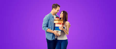 Love, relationship, dating, flirting, lovers, romantic concept - happy young couple holding gift boxes, close to each other. Purple violet background. Valentines Day holiday. Copy space area.の写真素材