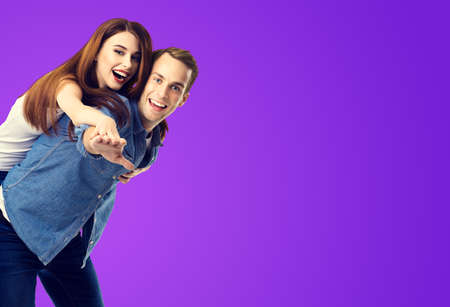 Love, relationship, dating, lovers, romantic concept - happy excited couple, in piggyback pose, over purple violet background. Valentines Day holiday. Copy space for text.の写真素材