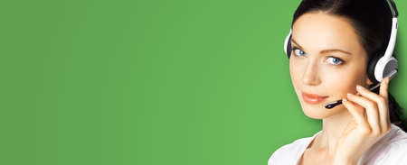 Call center help line service. Studio portrait image of customer support phone sales operator in headset, over green color background. Brunette business woman. Caller worker.の写真素材