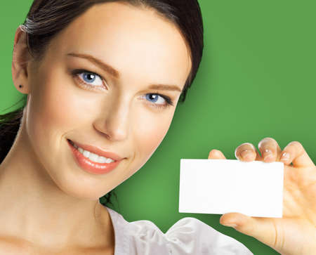 Closeup portrait of smiling businesswoman showing mockup empty businesscard or plastic credit card, with copy space for sign, over green color background. Brunette business woman at studio image.の写真素材