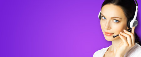 Call center help line service. Studio portrait image of customer support phone sales operator in headset, over violet purple background. Brunette business woman. Caller worker.の写真素材
