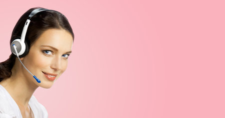Call center help line service. Studio portrait of customer support phone sales operator in headset, over rose pink background. Happy smiling business woman. Caller worker.の写真素材