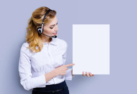 Call Center Service concept - customer support or sales agent. Businesswoman or caller or receptionist phone operator pointing at mock up sign board with copy space. Helping, answering, consulting.の写真素材