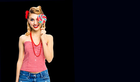 Half face portrait of excited woman holding lollipop covering one eye. Pin up girl with happy smile....