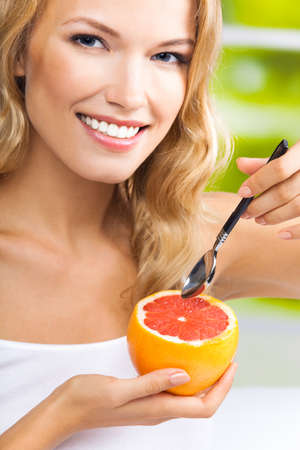 Portrait of happy smiling young woman with grapefruit, indoors. Healthy eating, vegetarian, antioxidants; keto ketogenic diet concept.の写真素材
