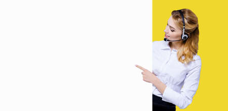 Call Center Service concept - customer support or sales agent. Businesswoman, caller, receptionist, phone operator point at signboard with copy space. Helping, answering, consulting. Yellow backgroundの写真素材