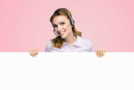 Call Center Service. Customer support or sales agent. Business woman or caller phone operator showing sign board or billboard with copy space. Helping, answering consulting. Rose pink color backgroundの写真素材