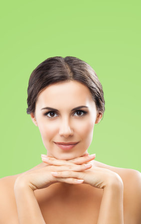 Portrait image of beautiful dark haired woman with hands near face, isolated over green color background. Brunette girl at studio. Beauty salon concept picture.の写真素材