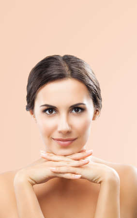 Portrait image of beautiful dark haired woman with hands near face, isolated over beige background. Brunette girl at studio. Beauty salon concept picture.の写真素材