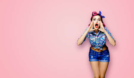 WOW! Portrait of woman holding her hands near open mouth and saying or shouting something. Pin up girl. Red purple haired model in retro vintage studio concept, on pink color. Copy space mock up.の写真素材