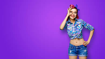 Pin up girl. Excited happy red purple haired woman show ok sign gesture, looking throw her hand. Retro and vintage image. Violet background with copy space. Ophthalmology ad concept.の写真素材