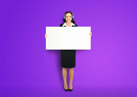 Call Center Service. Customer support or sales agent. Businesswoman or caller phone operator hold white banner. Full body of business woman in headset with empty signboard. Violet purple background.の写真素材