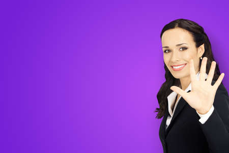 Excited smiling positive businesswoman in black confident suit showing five fingers, violet purple background. Happy gesturing brunette woman at studio. Business success concept.の写真素材