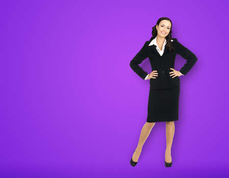 Full body length of happy smiling businesswoman with hands on hips, copy space area for some text. Confident woman in black suit stand violet purple background. Business concept.の写真素材