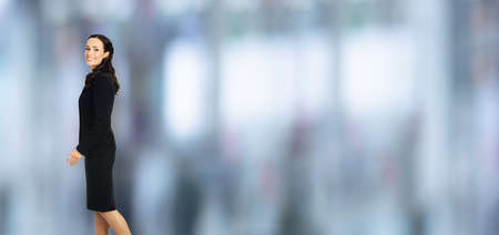 Profile side portrait of happy excited smiling businesswoman going side away, over copy space area. Waking confident business woman in black suit, blurred office backgroundの写真素材
