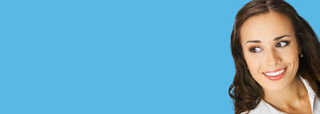 Portrait of happy excited smiling woman in white confident clothing, copy space text area. Business concept. Isolated on blue color background. Brunette businesswoman. Wide image.の写真素材