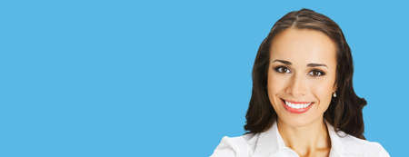 Businesswoman in white confident clothing, isolated on bright blue color background. Portrait of happy smiling brunette woman at studio. Business concept photo.の写真素材