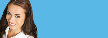 Portrait of happy excited smiling woman in white confident clothing, copy space text area. Business concept. Isolated on blue color background. Brunette businesswoman. Wide image.の写真素材