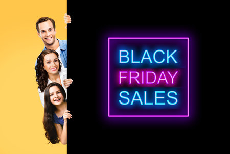 Family portrait image - smiling father, mother and little daughter peek out from behind big board, isolated over yellow background. Paper broadsheet with black friday sales text signの写真素材