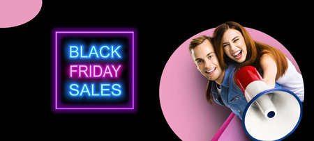 Happy excited couple with megaphone and shopping bags. Man and woman shout saying in loudspeaker mega phone. Big deals, discounts offers concept. Black Friday sales neon light sign. Pink back.の写真素材