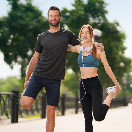 Portrait of young smiling couple, woman training with man or bearded coach trainer, doing stretching exercise, before morning jogging, outdoors. Fitness, sport, city workout, wellness concept. Squareの写真素材