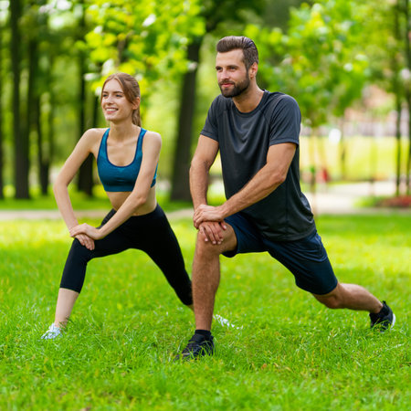Square image - young smiling couple, woman training with man or bearded coach trainer, do squat fit exercise together, looking forward, outdoor. Fitness, sport, workout, healthy lifestyle concept.の写真素材