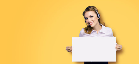 Call Center Service. Customer support or sales agent. Businesswoman or caller or receptionist phone operator showing mockup empty signboard. Helping, answering, consulting. Orange yellow background.の写真素材