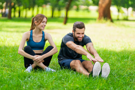 Image of young smiling couple, woman training with man or bearded coach trainer, doing stretching exercise, before morning jogging, outdoors. Fitness, workout, healthy lifestyle concept.の写真素材