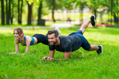 Image of young smiling couple, woman training with man or bearded coach trainer, doing lath fit exercise together, looking forward ahead, outdoors. Fitness sport, healthy lifestyle conceptの写真素材
