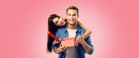 Holiday sales actions, rebates, discounts offers concept image - happy couple opening gift box, isolated on vivid rose pink background. Copy space for some text.の写真素材