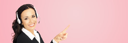 Call center service. Portrait of customer support phone sales operator in headset showing something or copy space area for text, imaginary, product or slogan, over rose pink background.の写真素材