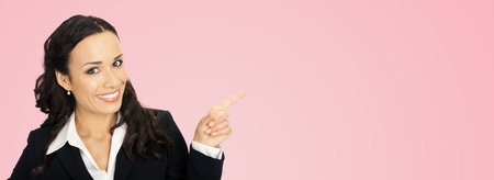 Happy smiling young beautiful business woman showing something or copyspase for product or sign text, isolated over rose pink backgroundの写真素材