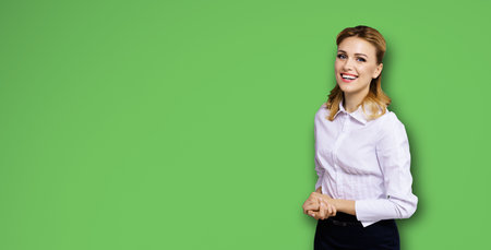 Happy smiling attractive businesswoman, with copy space area for some slogan or text. Confident blond woman in white shirt, on bright green background. Business concept.の写真素材
