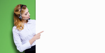 Call Center Service concept - customer support or sales agent. Businesswoman, caller, phone operator pointing finger at signboard with copy space. Help, answering, consulting. Bright green backgroundの写真素材